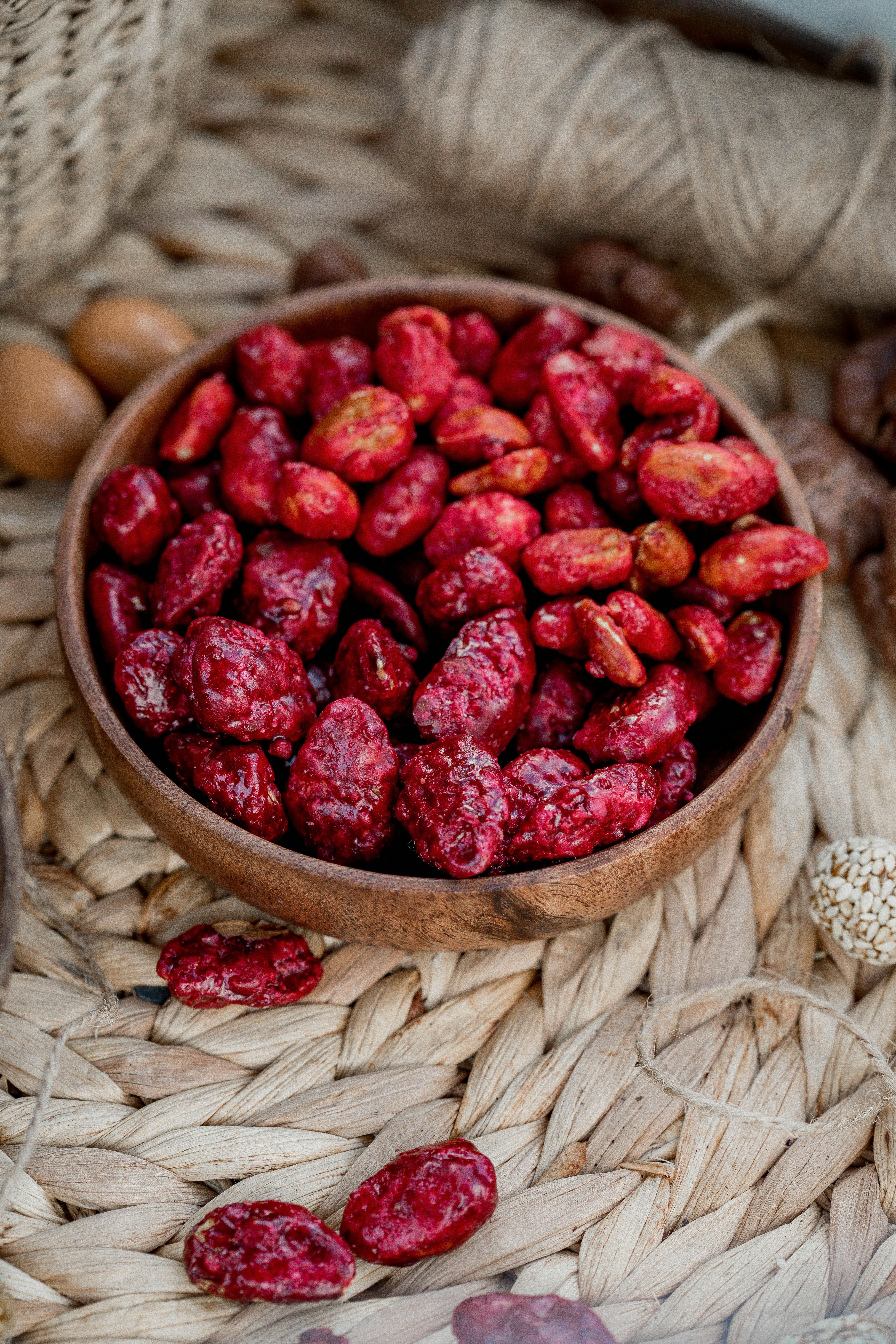 Close-up of vibrant red dried berries in a wooden bowl on woven placemat.